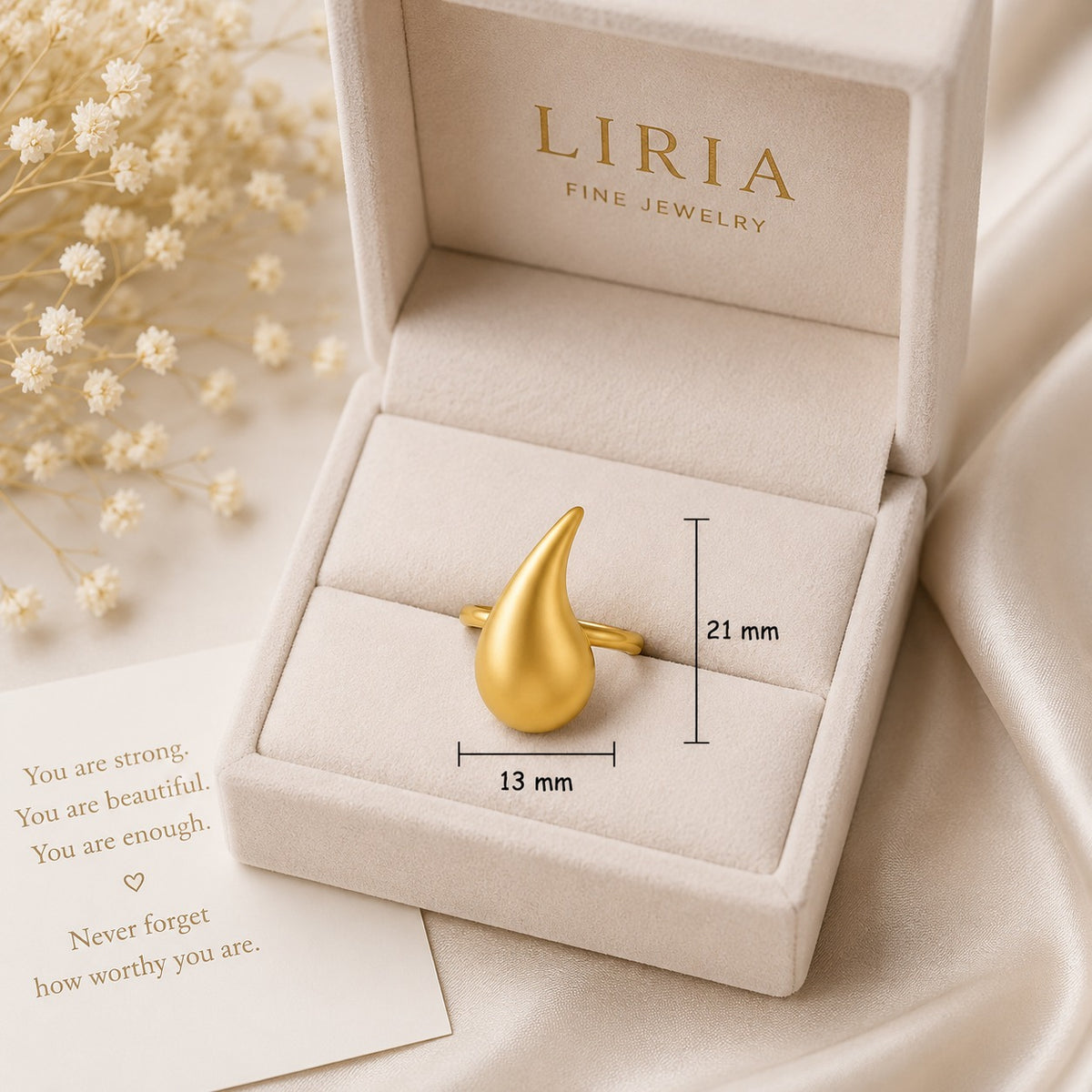 Gold ring in a LIRIA jewelry box with a motivational card and flowers.
