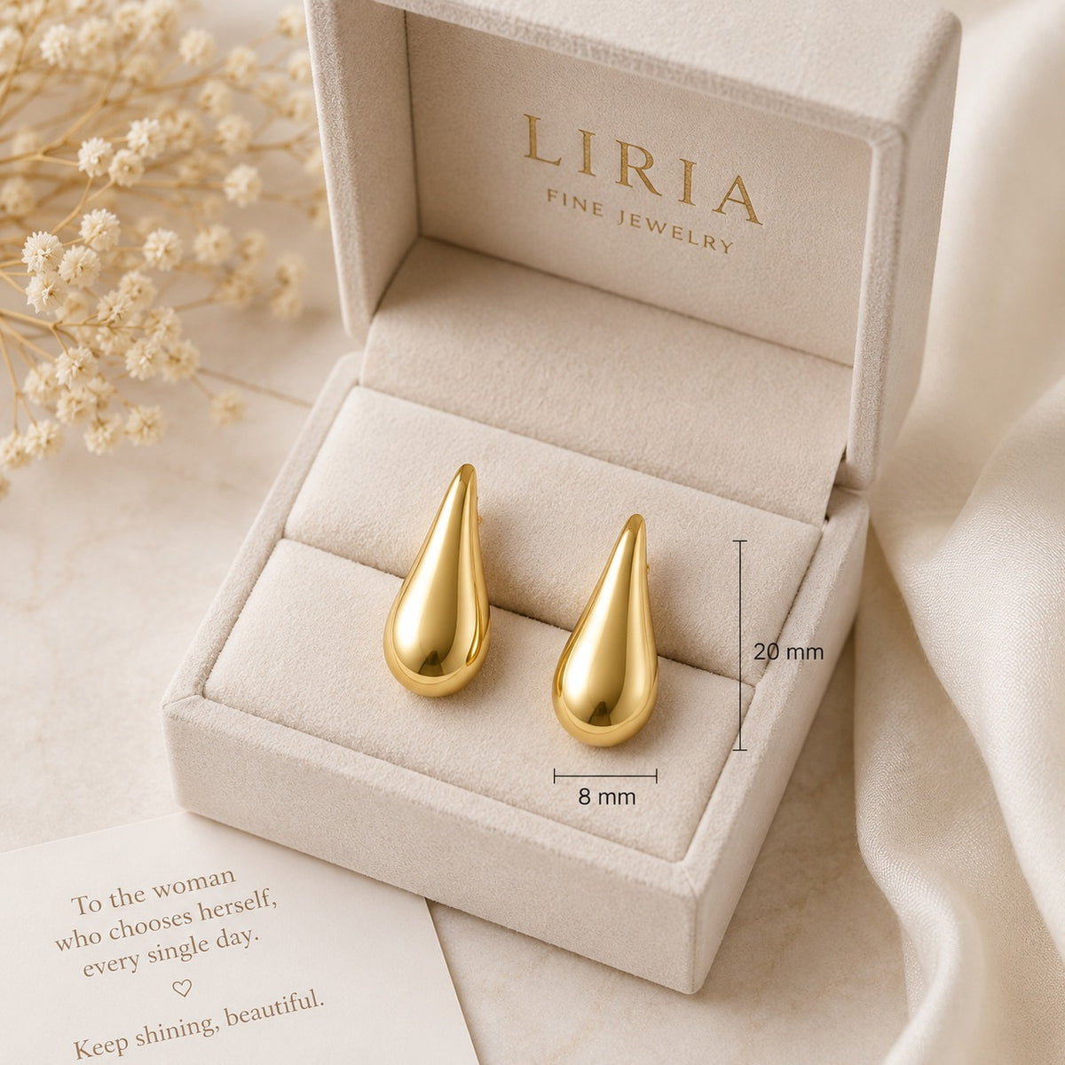 Gold teardrop earrings in a LIRIA jewelry box with dried flowers and a quote card.