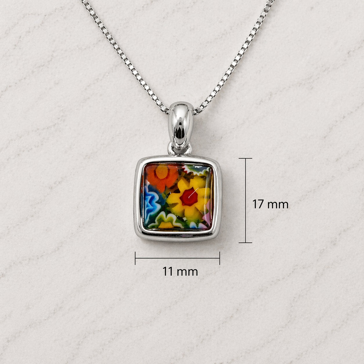 Silver pendant with colorful floral design on a white textured background