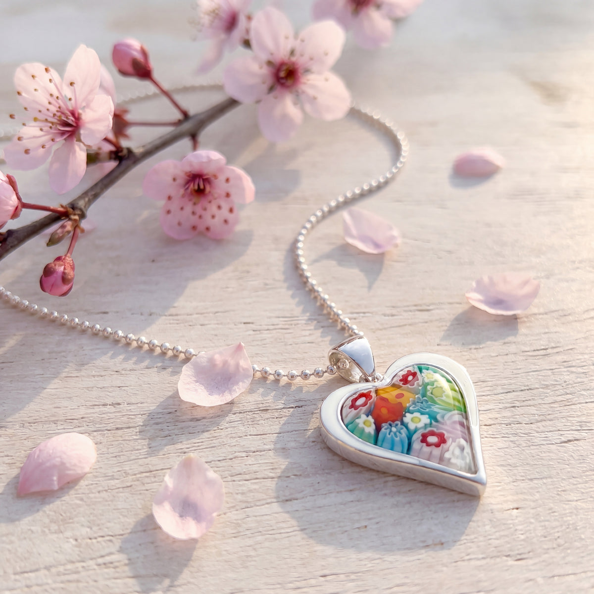 Heart-shaped pendant with floral design on a cherry blossom branch