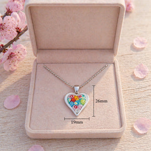 Heart-shaped floral pendant necklace in a box with cherry blossoms in the background