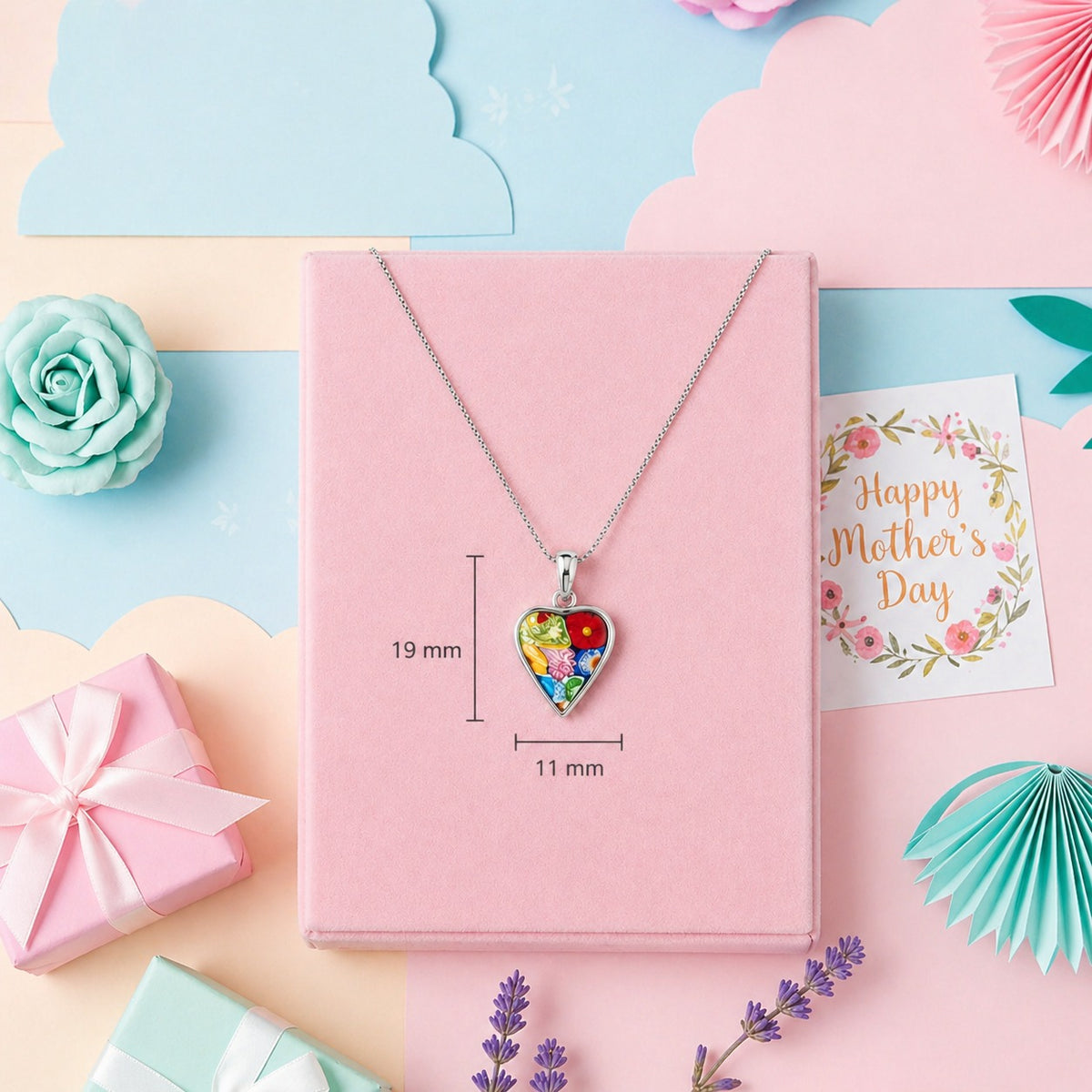 Heart-shaped colorful pendant necklace in a pink box with floral decorations and a 'Happy Mother's Day' card.