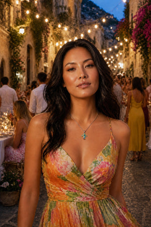 Woman in a colorful dress standing in an outdoor evening setting with string lights and people in the background.