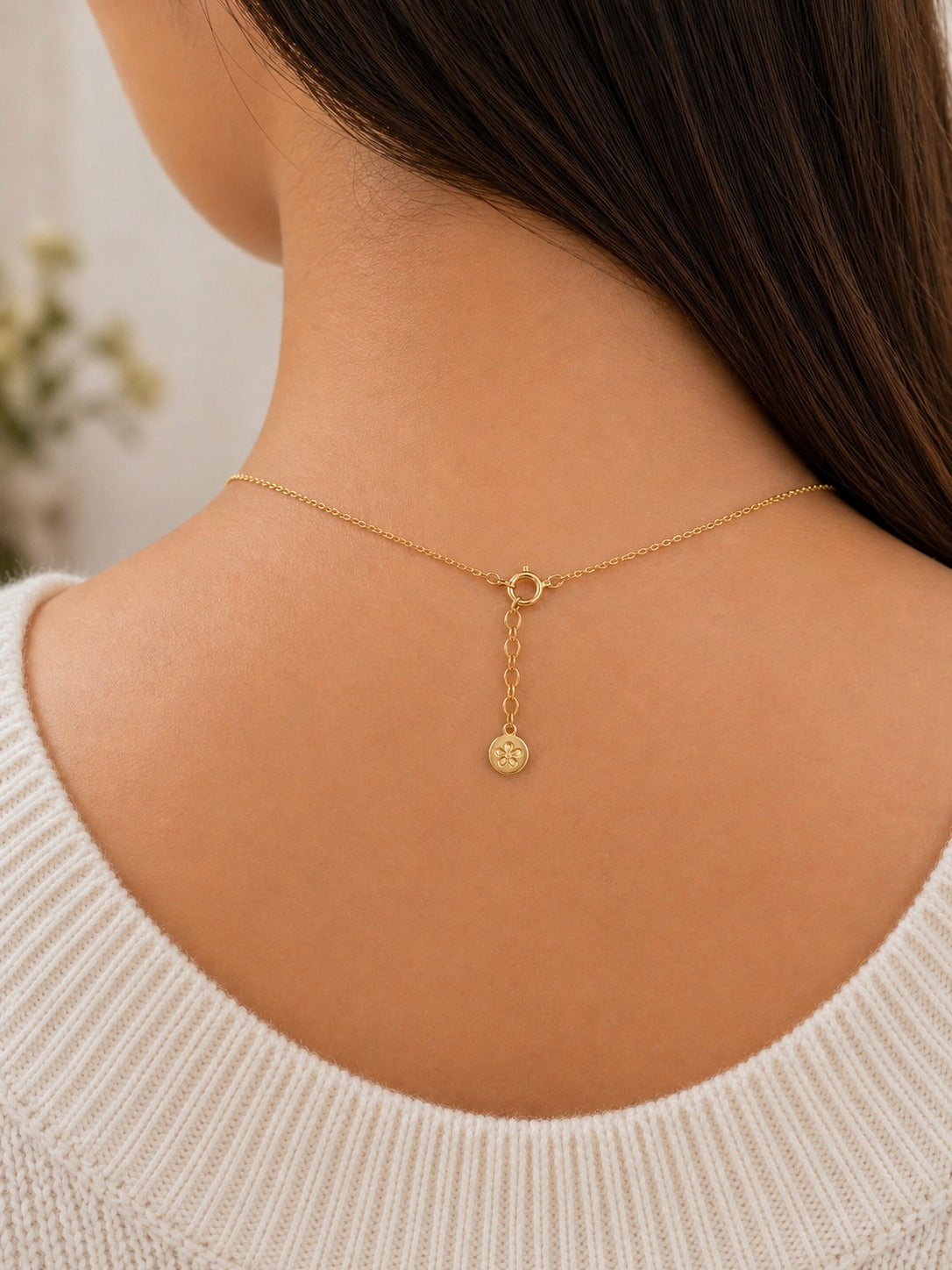 Gold necklace on a person wearing a white sweater with a blurred background
