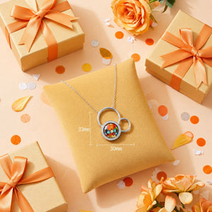 Necklace with a colorful pendant on a yellow pillow surrounded by gift boxes and flowers on a peach background