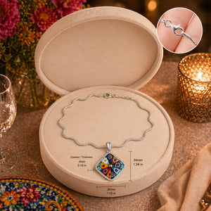 Necklace with a colorful pendant in an open jewelry box on a decorative table.