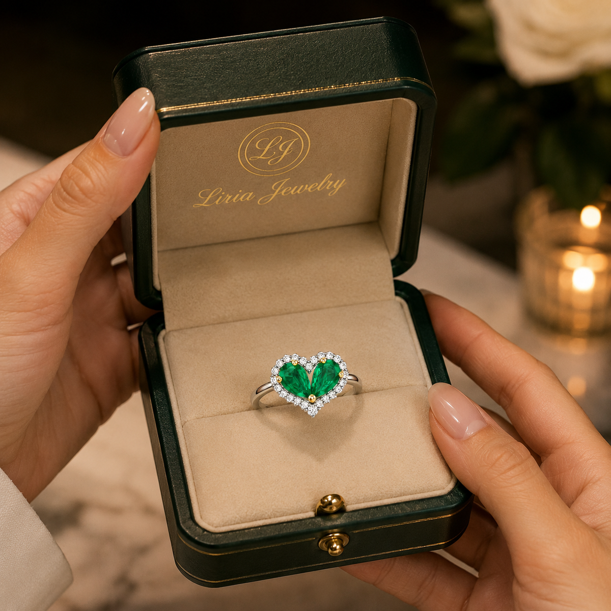 Heart-shaped green gemstone ring displayed in an elegant Liria Jewelry ring box held in both hands.
