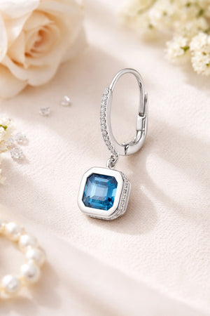 Silver earring with a blue gemstone on a soft background