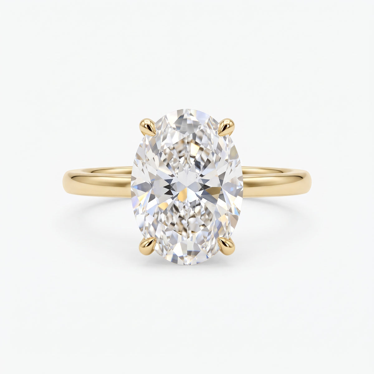 An oval-cut diamond engagement ring with a yellow gold band, shown on a clean, light gray background.