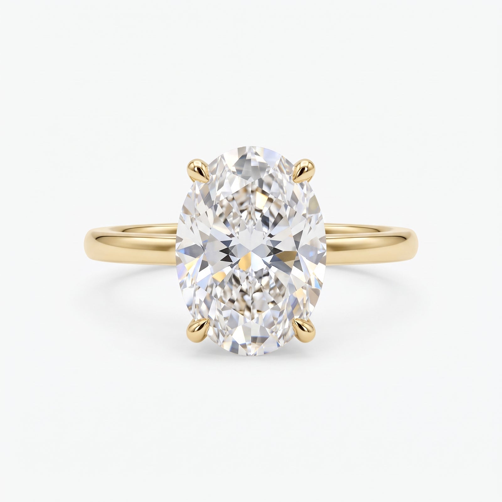 An oval-cut diamond engagement ring with a yellow gold band, shown on a clean, light gray background.