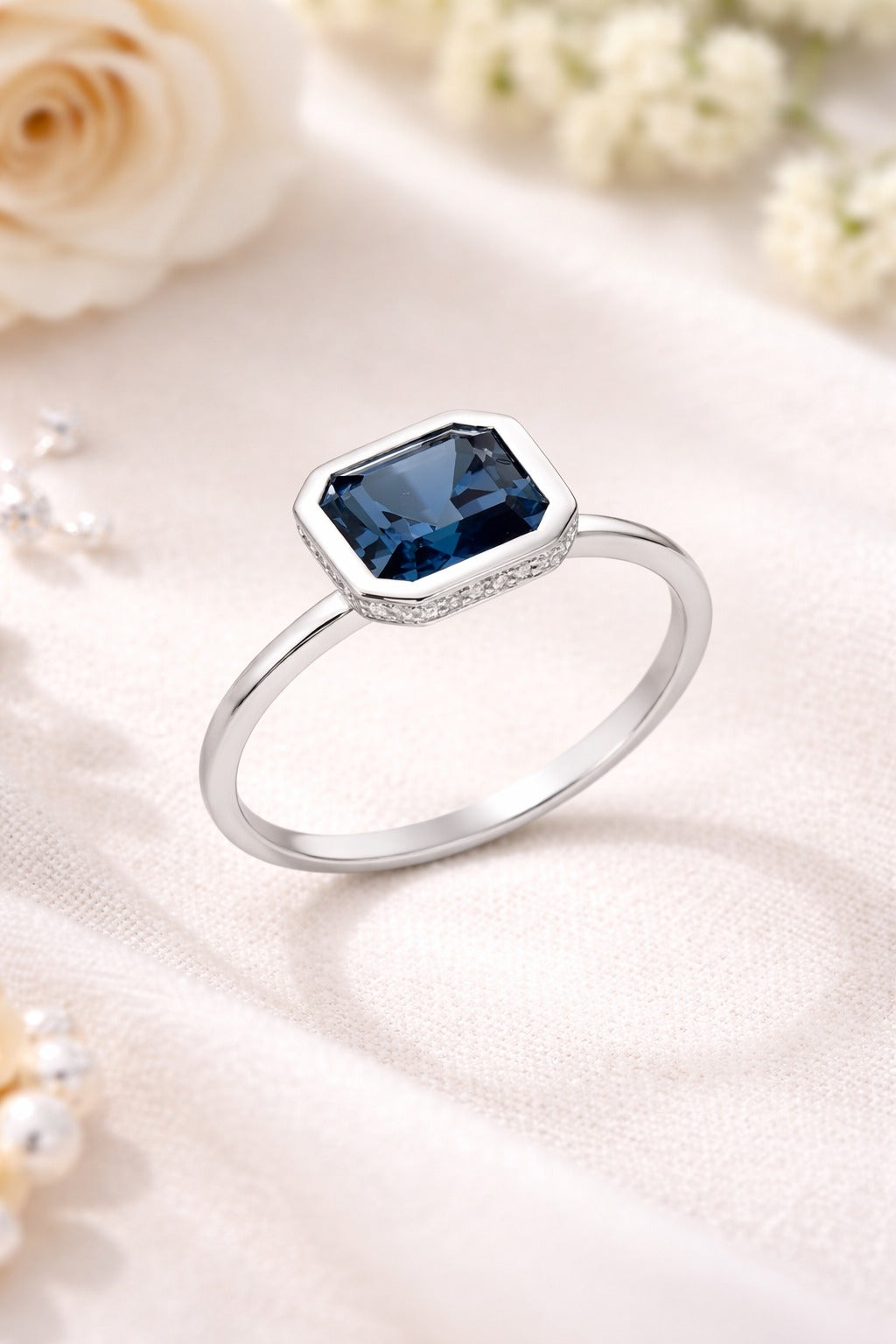 Silver ring with a blue gemstone on a soft white background