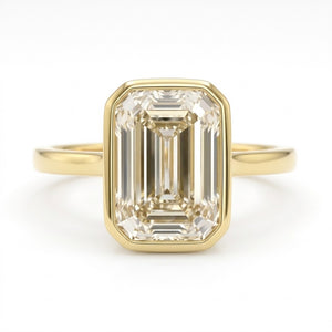 A yellow gold ring featuring a large rectangular emerald-cut clear gemstone in a bezel setting, shown against a plain white background.