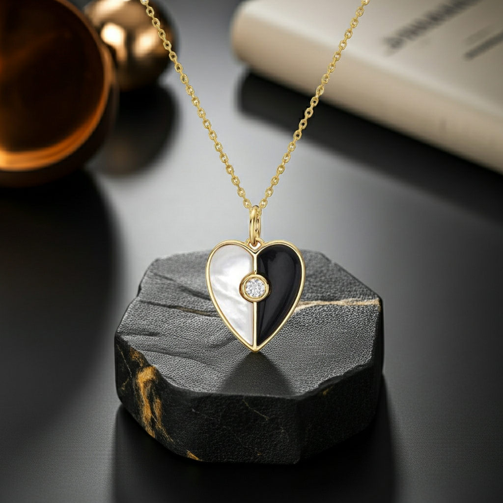 Heart-shaped pendant necklace with black and white design on a dark stone surface