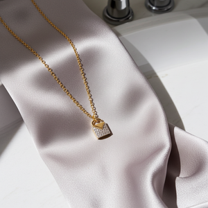 Gold necklace with a lock-shaped pendant on a light fabric background