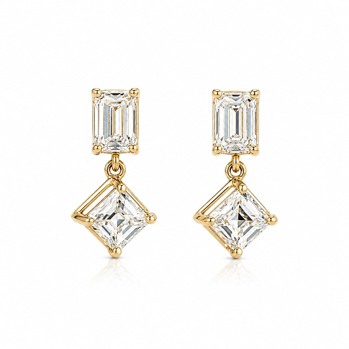 A pair of gold drop earrings featuring a rectangular baguette-cut clear gemstone in the top setting and a larger square princess-cut clear gemstone in the bottom setting, shown on a clean white background.