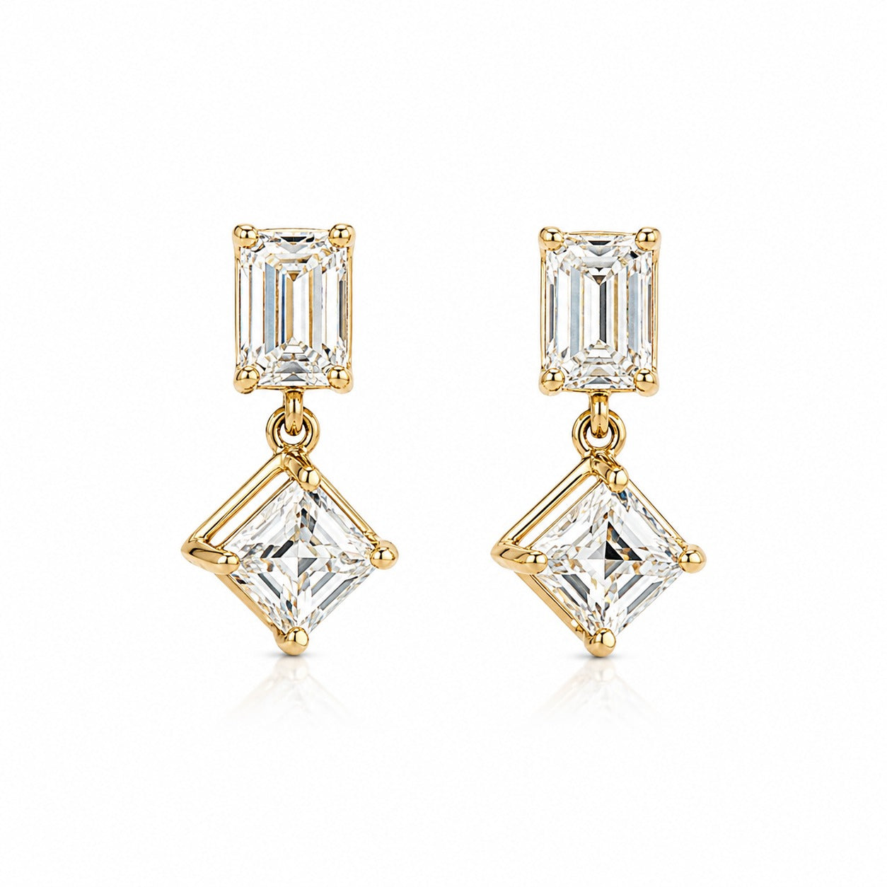 A pair of gold drop earrings featuring a rectangular baguette-cut clear gemstone in the top setting and a larger square princess-cut clear gemstone in the bottom setting, shown on a clean white background.