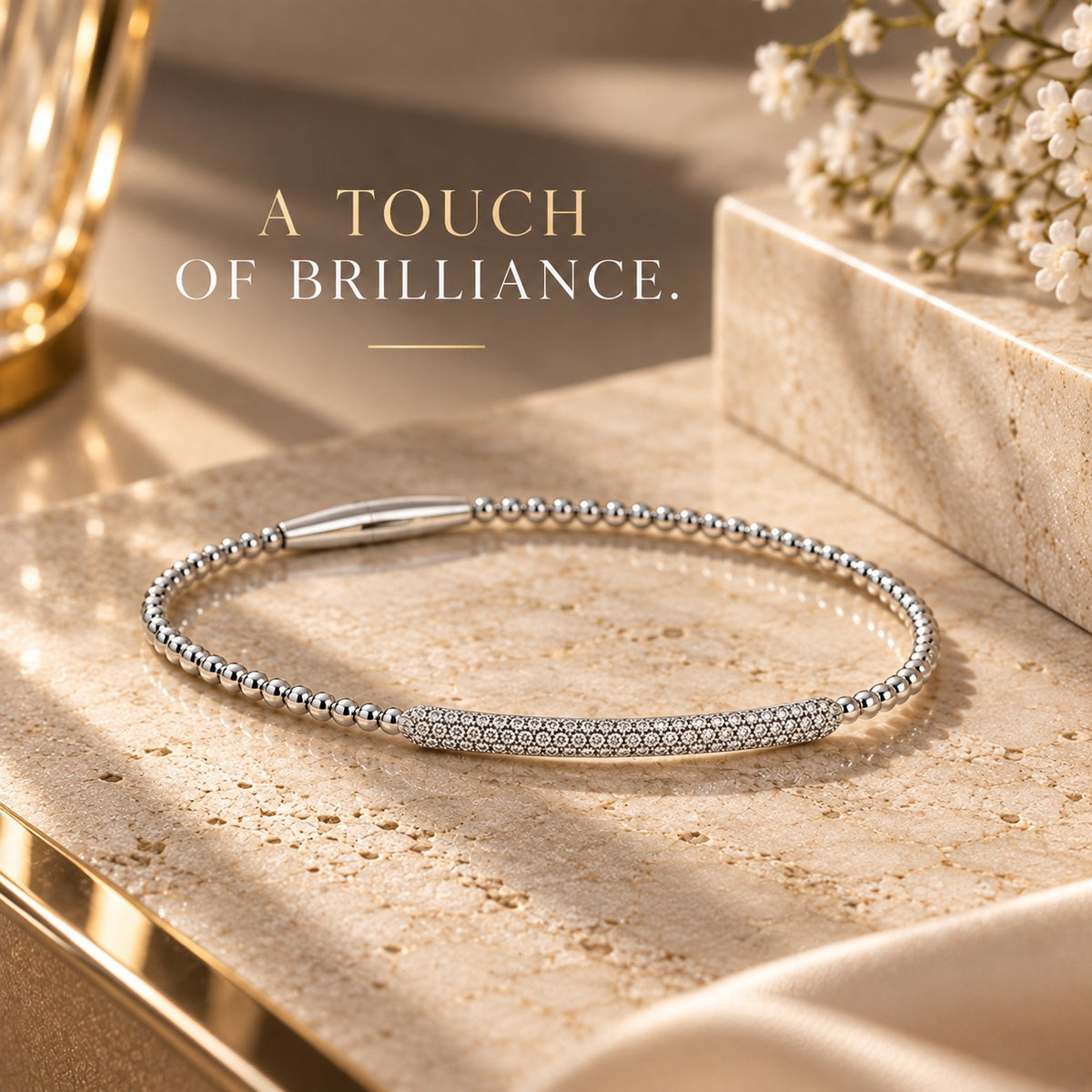 14K white gold diamond bracelet with a delicate beaded design and pavé diamond centerpiece displayed on an elegant beige marble background.