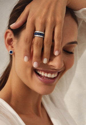 14K white gold open band ring featuring a vivid blue sapphire center row framed by two sparkling diamond rows.