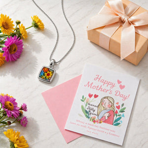 Necklace with floral pendant, gift box, and Mother's Day card on a light surface with flowers.