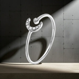 Silver ring with a crescent moon design on a dark concrete background