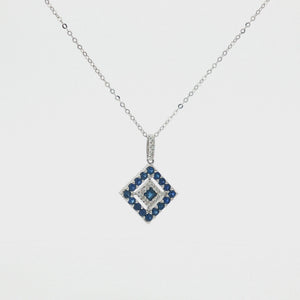 A delicate 14K white gold chain necklace featuring a geometric diamond-shaped pendant adorned with natural blue sapphires and sparkling white diamonds, displayed on a clean white studio background.