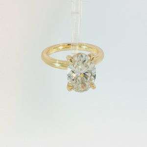 An oval diamond engagement ring with a yellow gold band, featuring a large oval-cut diamond set in a four-prong gold setting on a clean white background.