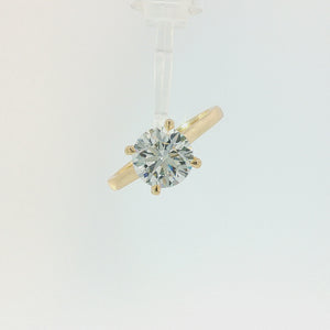 A classic solitaire engagement ring featuring a round brilliant-cut diamond set in a polished yellow gold four-prong setting, on a clean white background.