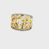 A wide gold ring featuring a geometric pattern of clear gemstones, including round, marquise, and baguette cuts, with diamond-paved borders on a white background.