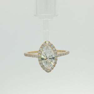 A yellow gold marquise-cut halo ring featuring a large central diamond surrounded by smaller diamonds on the band, set against a plain white background.