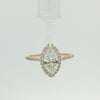 A yellow gold marquise-cut halo ring featuring a large central diamond surrounded by smaller diamonds on the band, set against a plain white background.
