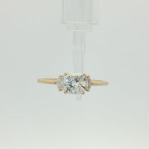 A yellow gold three-stone engagement ring featuring a large cushion-cut center diamond flanked by two marquise-cut side diamonds, set against a plain white background.