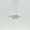 A yellow gold three-stone engagement ring featuring a large cushion-cut center diamond flanked by two marquise-cut side diamonds, set against a plain white background.