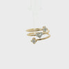 A gold snake-style wrap bracelet featuring a central pavé heart and two flower motifs, each set with clear stones, shown on a plain white background.