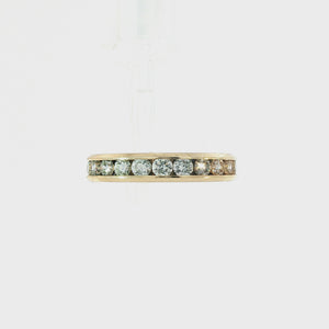 A yellow gold eternity ring featuring a row of round brilliant-cut diamonds set in a polished band, shown against a plain white background.