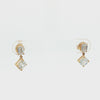 A pair of gold drop earrings featuring a rectangular baguette-cut clear gemstone in the top setting and a larger square princess-cut clear gemstone in the bottom setting, shown on a clean white background.