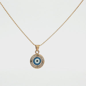 Liria Jewelry Evil Eye Necklace displayed in an open cream-colored presentation box, with product text and decorative elements on a warm beige background.