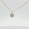 A gold chain necklace with a square pendant featuring a border of small clear stones and a central cluster of clear stones, shown on a plain white background.