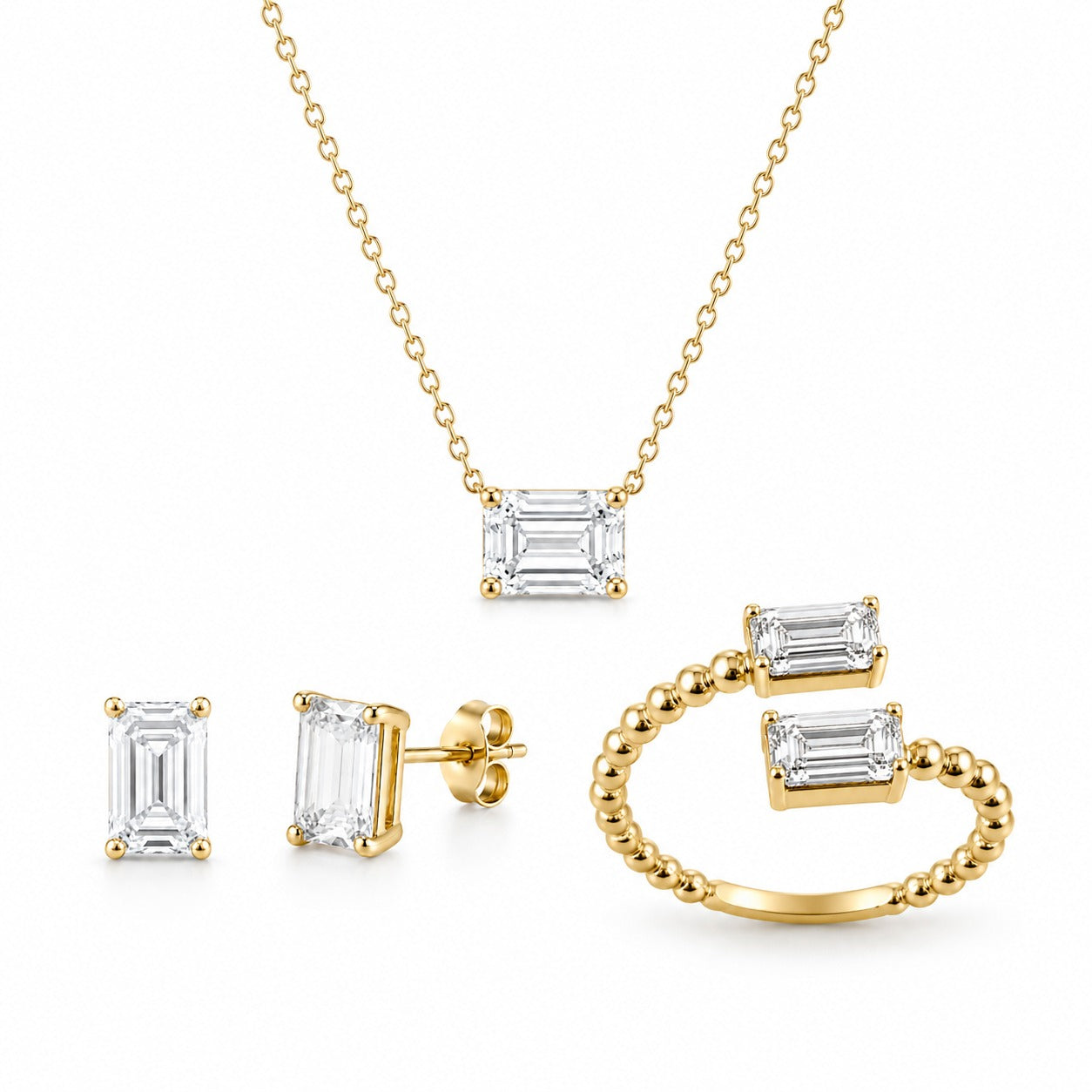 Gold jewelry set with emerald-cut gemstones on a white background