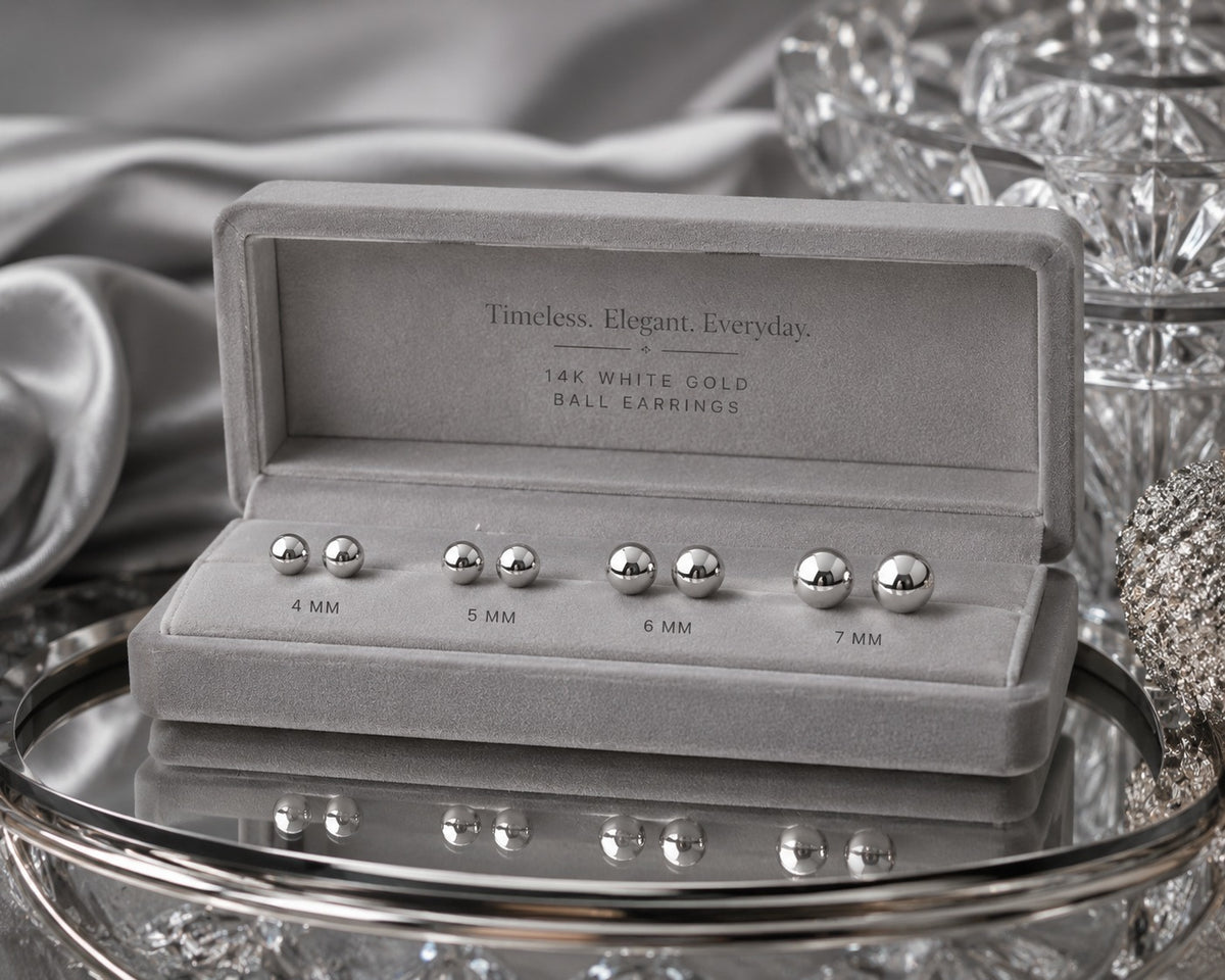 Silver ball earrings in a display case with 'Timeless. Elegant. Everyday.' text on a reflective surface.
